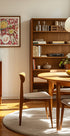 a cozy dining room with a wooden table and chairs, a bookshelf, and a framed artwork on the wall.