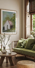 a cozy living room with a large window, a green sofa, a wooden coffee table, and a framed painting of a house.